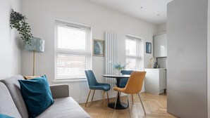 A modern living room with a grey sofa, blue chairs, and a small dining table. - 1 Bedroom Center London Luxury Pad, High Spec (Greater London)
