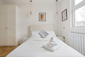 A bedroom with a bed, white walls, a window, and a radiator. - 1 Bedroom Center London Luxury Pad, High Spec (Greater London)