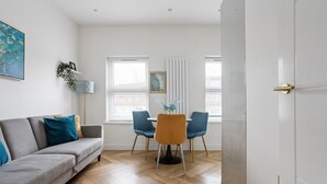 A modern living room with a grey sofa, blue chairs, a round table, and a white door. - 1 Bedroom Center London Luxury Pad, High Spec (Greater London)