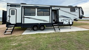 A large RV with a sliding door, a ladder, and a ramp leading to the entrance. - Joy Drive In Movie & RV Resort - Montana - Joy Drive In Movie & RV Resort - Montana (Copperas Cove)