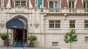 Ein historisches Gebäude mit einer schwarzen Markise, die die Zahl 1619 zeigt, einer Flagge und zwei Pflanzkübeln.
