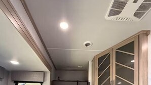 A compact RV interior with a sofa, a TV, and cabinets. - Joy Drive In Movie & RV Resort - 2bd Toy Hauler - Joy Drive In Movie & RV Resort - 2bd Toy Hauler (Copperas Cove)