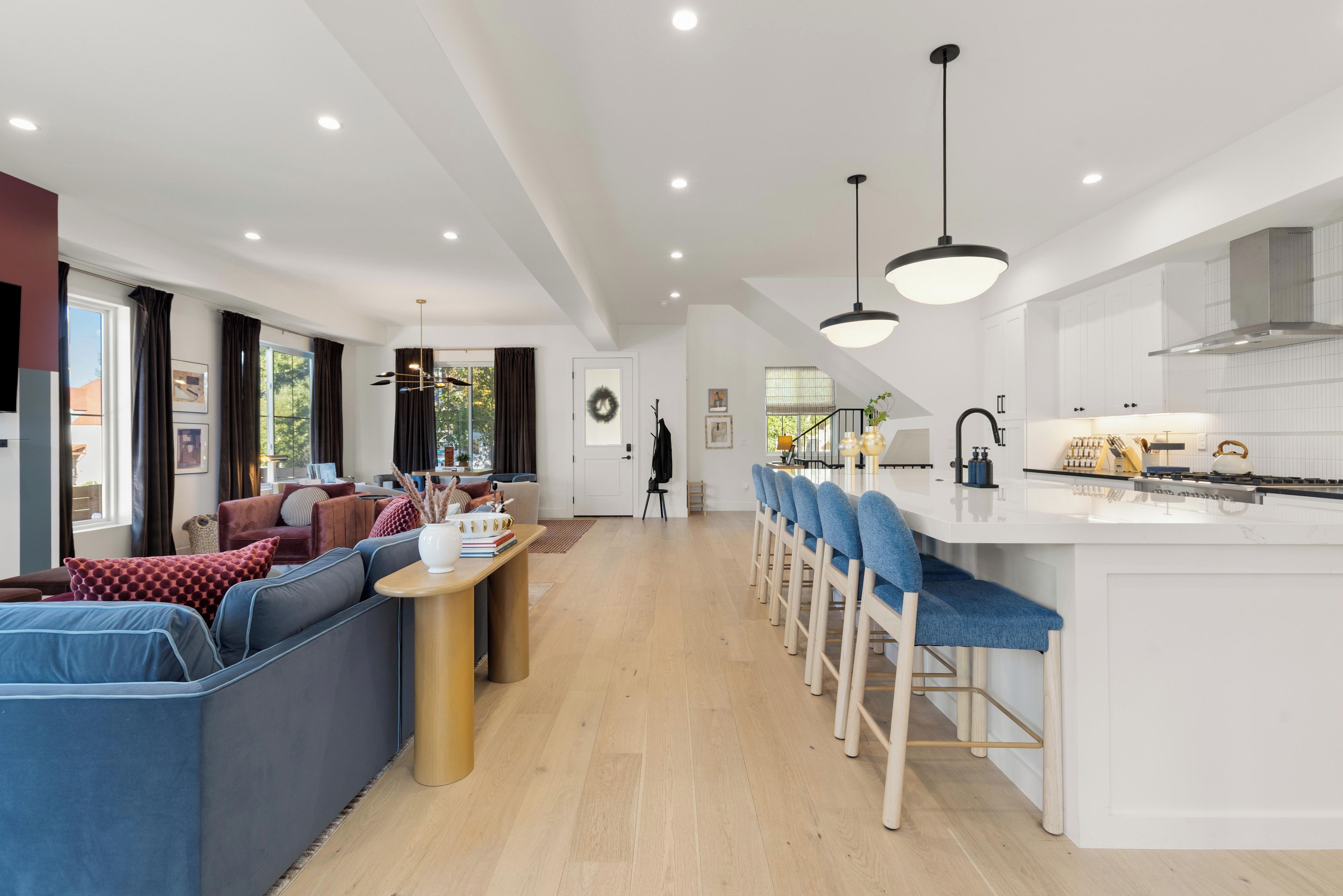 A modern kitchen with white cabinetry, a central island, and bar stools.