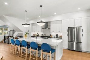 A modern kitchen with a large island, stainless steel appliances, and blue bar stools. - Game night in your theater, stargazing from the hot tub. Sunday brunch in a chef's kitchen (or with our optional private chef, Marvin). The Benton is a 3,600 sq ft experience in one of Denver's coolest neighborhoods. (Denver)