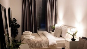 Un dormitorio ordenado con cama, mesitas de noche y una planta en maceta.