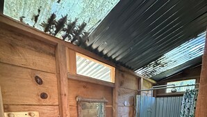 Ein rustikales Badezimmer aus Holz mit Waschbecken, Spiegel, Toilette und Duschbereich.