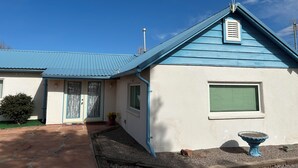 Une maison avec un toit bleu, un petit porche et une fenêtre avec des volets.