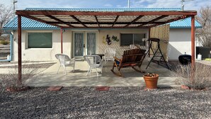 Un patio couvert avec des meubles d’extérieur, un barbecue et un petit jardin.