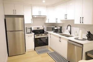 Una cucina moderna con mobili bianchi, elettrodomestici in acciaio inossidabile e un rubinetto nero.