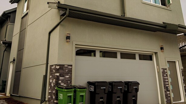 A two-story house with a garage and a driveway. There are four trash bins in front of the house. - suite, Cozy & Fully Equipped. (Edmonton)