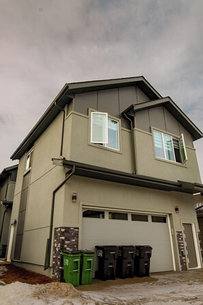A two-story house with a garage and a driveway. There are four trash bins in front of the house. - suite, Cozy & Fully Equipped. (Edmonton)