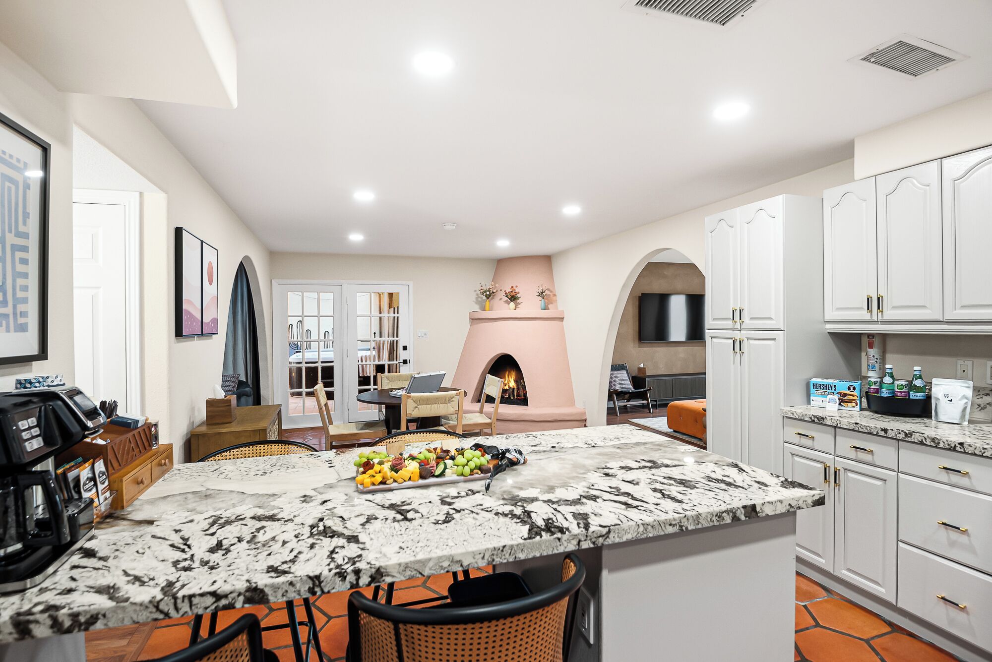 A modern kitchen with a marble countertop, a built-in oven, and a fireplace.