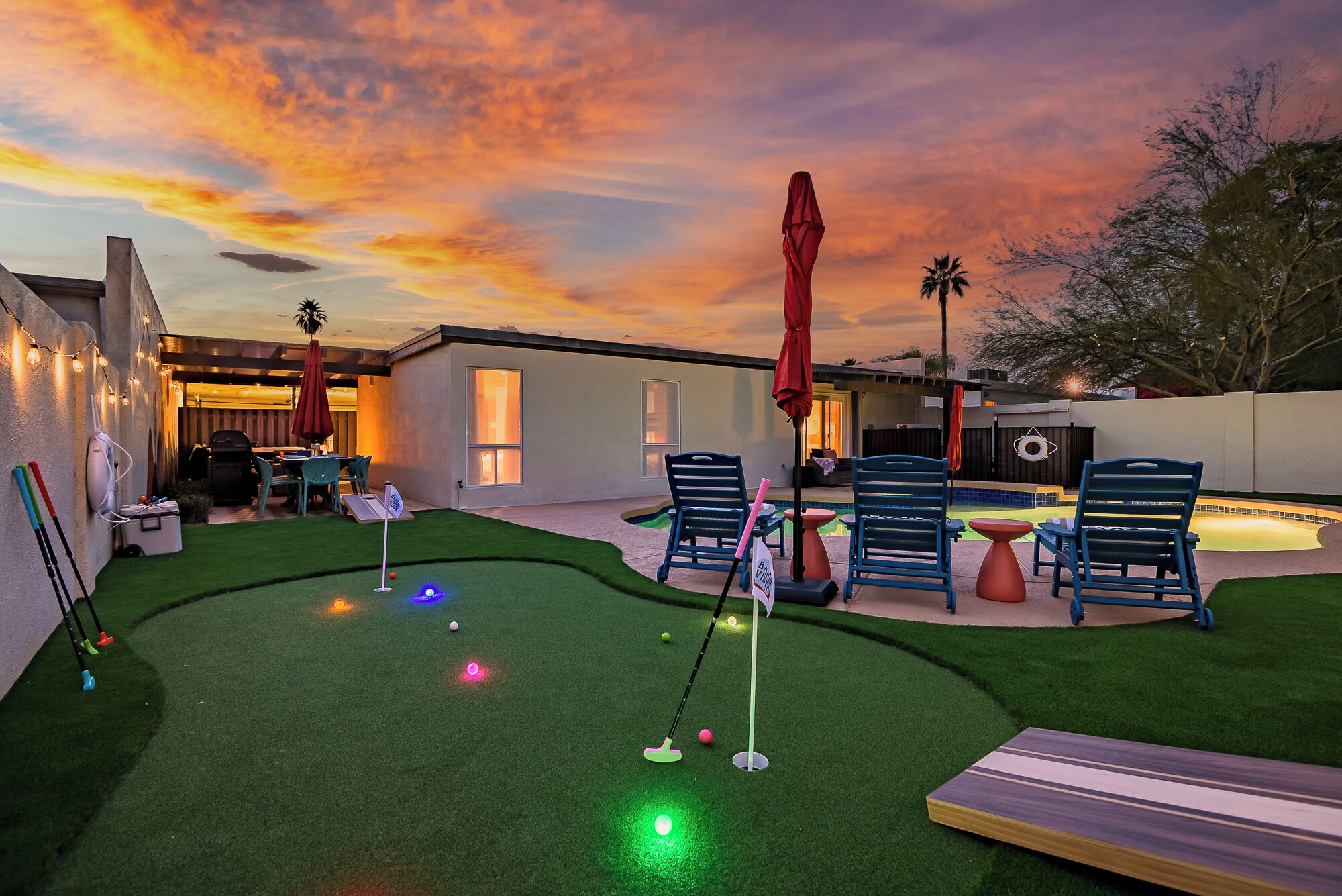 A backyard with artificial grass, a putting green, and outdoor furniture.