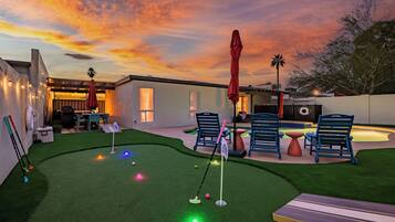 A backyard with artificial grass, a putting green, and outdoor furniture.