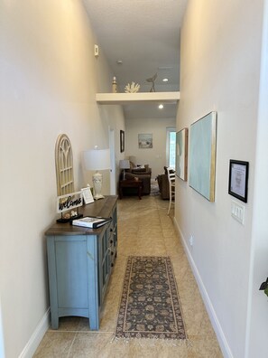 A hallway with a reception desk, a patterned rug, and artwork on the walls.
