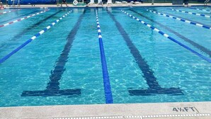 En swimmingpool med linedelere, et overdækket tilskuerområde og et højt lysmast.