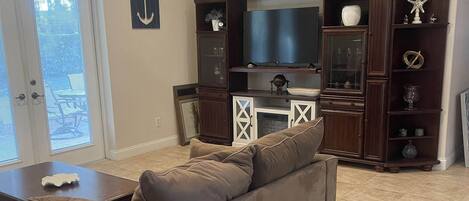 A living room with a sofa, television, and wooden cabinet.
