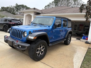 Un Jeep Rubicon bleu est garé dans une allée.