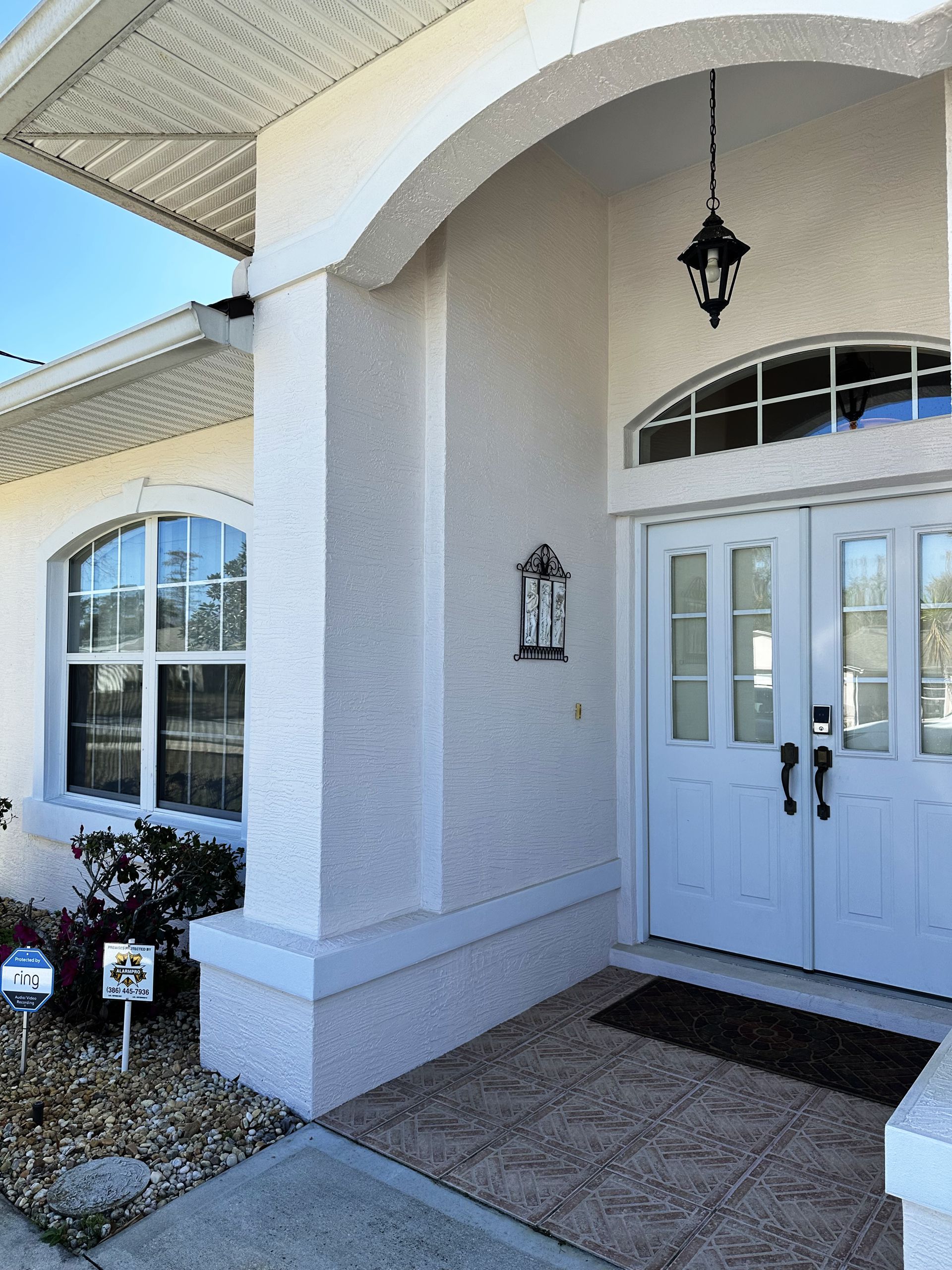 A building with a white exterior, a covered entrance, and a door with a keypad lock.