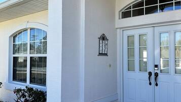 A building with a white exterior, a covered entrance, and a door with a keypad lock.