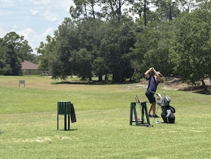 Un campo de golf con un tee, un putting green y un marcador de bandera.