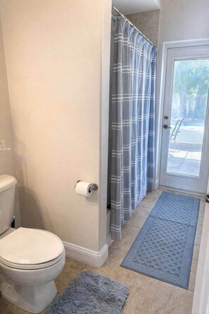Un baño con inodoro, cortina de ducha y puerta que da al exterior.