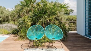 A wooden deck with two turquoise chairs, a pool, and lush greenery. - Villa Zabbara, independent and private pool (CASTELLAMMARE DEL GOLFO)