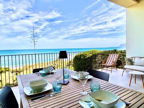 A dining table set with glassware and plates, overlooking a beach with a clear sky. - Riva Marina, on the beach (ALCAMO)