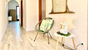 Um corredor com uma cadeira e uma pequena mesa com um objeto decorativo.
