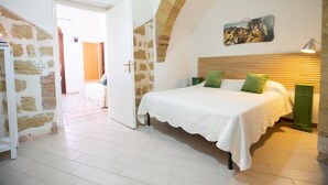 Ein Schlafzimmer mit einem Bett, einem hölzernen Kopfende, einem grünen Nachttisch und einer Steinwand.