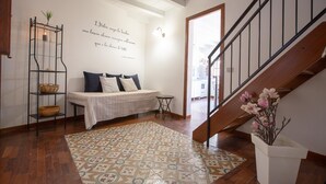 Ein Zimmer mit einer Couch, einem gemusterten Teppich, einer Wand mit einem Zitat, einer Treppe und einem Topfpflanzen.