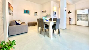 A modern living room with a dining area, a sofa, a coffee table, and a TV. - Villa dei Gerani, 500 mt from the sea. (ALCAMO)