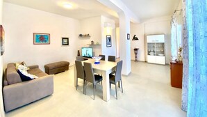 A modern living room with a dining area, a sofa, a coffee table, and a TV. - Villa dei Gerani, 500 mt from the sea. (ALCAMO)