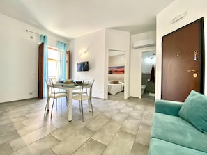 Ein modernes Wohnzimmer mit Essbereich, einem an der Wand montierten Fernseher und einer Couch.