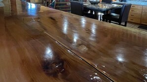 Un intérieur spacieux de chalet en bois, avec un bar en bois poli, une cheminée en pierre et une tête de cerf accrochée au mur.