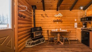 Ein rustikales Holzhaus-Interieur mit Essbereich, Kamin und Küche.