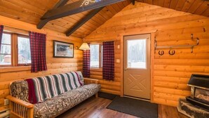 Ein gemütliches Blockhaus-Interieur mit einer Holzsofa, einem Kamin und Karomustert-Vorhängen.
