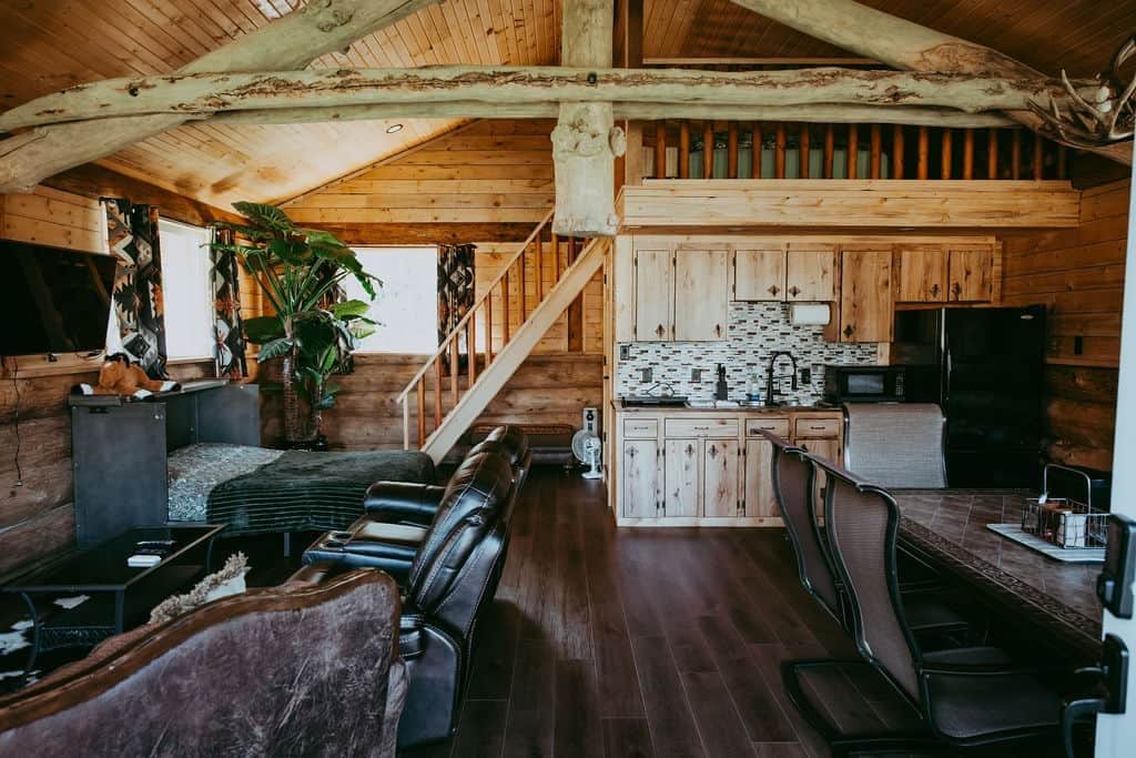 L’intérieur d’un chalet rustique comprend un coin repas, une cuisine et un escalier.