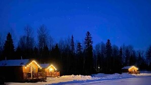 A snow-covered landscape with two illuminated cabins at dusk. - The Mustang Cabin - Bear Creek Cabins (County Of Wetaskiwin No. 10)
