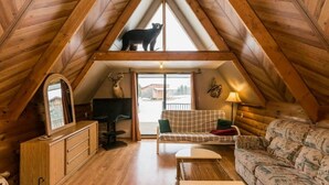 A cozy attic bedroom with a sloped ceiling, a wooden desk, a sofa, and a bed.