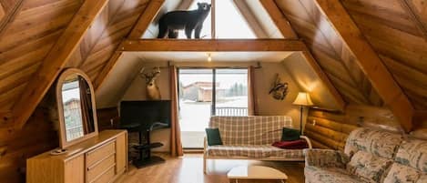A cozy attic bedroom with a sloped ceiling, a wooden desk, a sofa, and a bed.