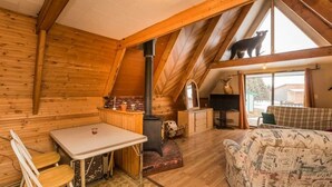 A cozy cabin interior with a wooden interior, a fireplace, a dining area, and a sofa.