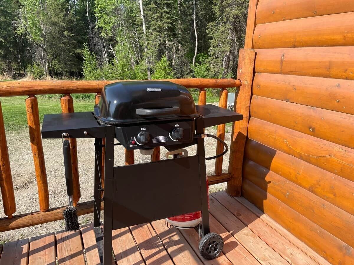 Un barbecue portable sur une terrasse en bois avec une rambarde en métal.