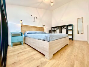 A bedroom with a wooden bed, a nightstand, a dresser, a mirror, and a hanging light fixture. - Loft Pergola, strategic location (CASTELLAMMARE DEL GOLFO)