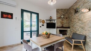 A dining area with a wooden table, chairs, a basket of fruit, a television, and a stone wall. - Villa Adele Alcamo, private pool and privacy (ALCAMO)