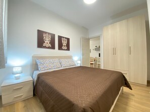 A bedroom with a bed, nightstands, a wardrobe, and two wall-mounted artworks. - Dimora di Angela 100 meters from the sea (ALCAMO)