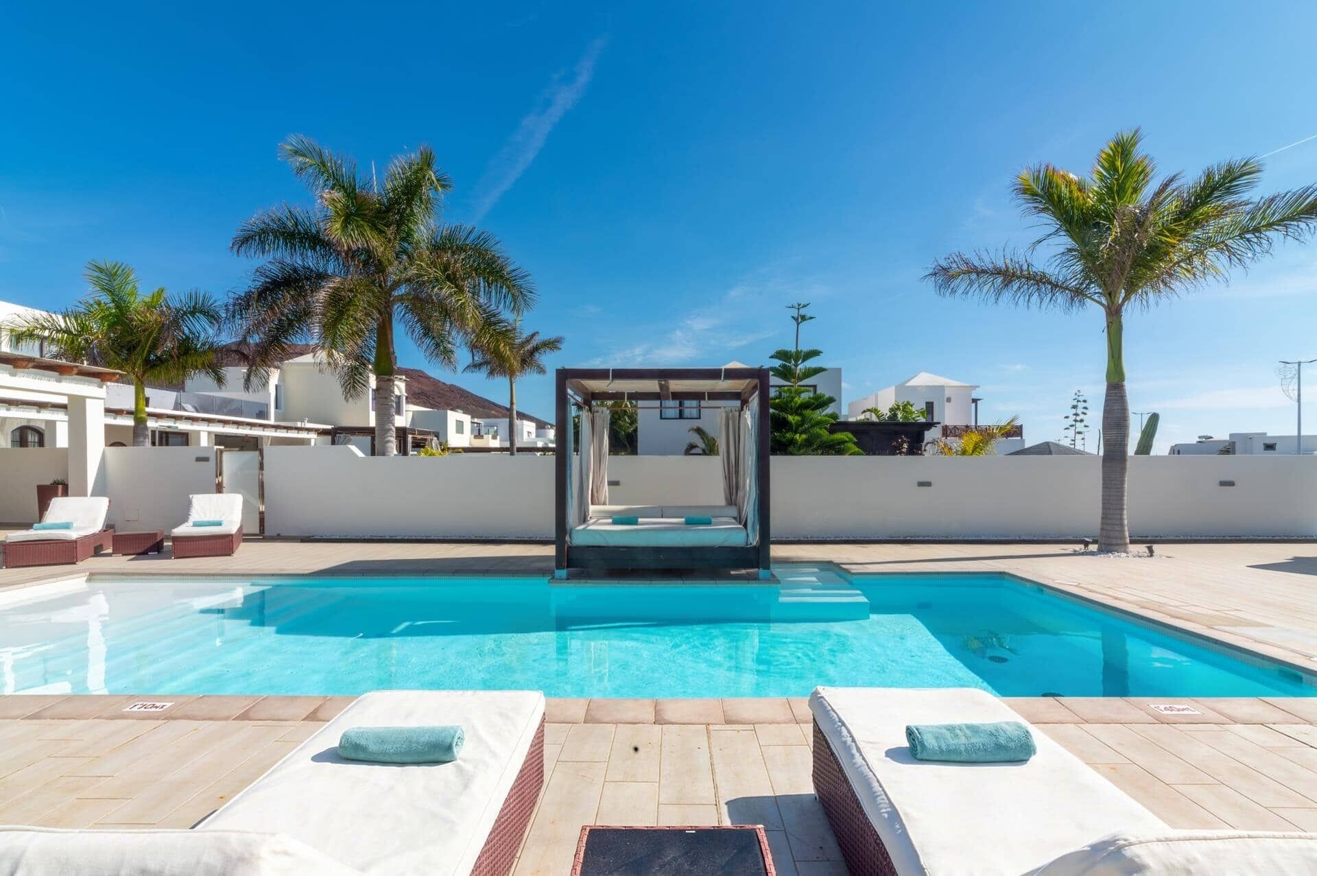 Piscina com espreguiçadeiras e toldo.