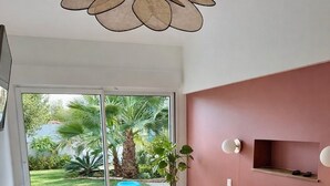 A bedroom with a large bed, a sliding glass door to a garden, and a modern ceiling light.