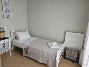 A small, neatly arranged bedroom with a single bed, a bedside table with a lamp, a radiator, and a wall-mounted picture frame. - Villa Armonia B by Corfu Stay Solutions, Villa (Corfu)