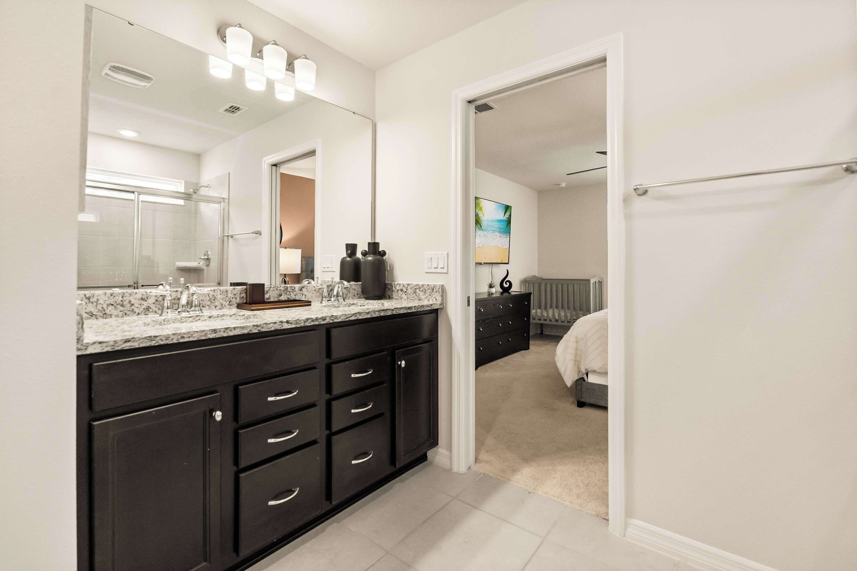 A modern bathroom with a large mirror, dark cabinets, and a shower area.